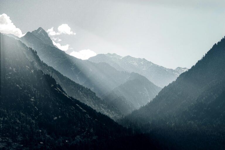 Breathtaking view of sunrays piercing through the misty mountains in Pahalgam, capturing the essence of serene nature.