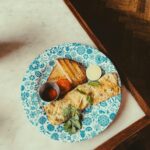 A savory breakfast omelette served with toast and tomato on a floral blue plate.