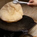 A homemade chapati being cooked on a stove, showcasing traditional Indian bread preparation.