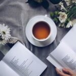 Inviting cozy reading setup with tea, poetry books, and fresh flowers on a table.